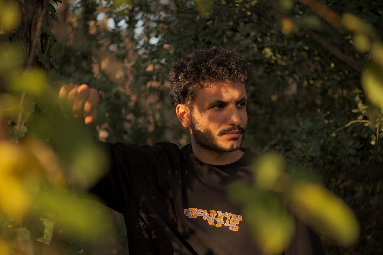 A thoughtful man standing amidst lush green foliage, enjoying a moment of reflected peace in nature.